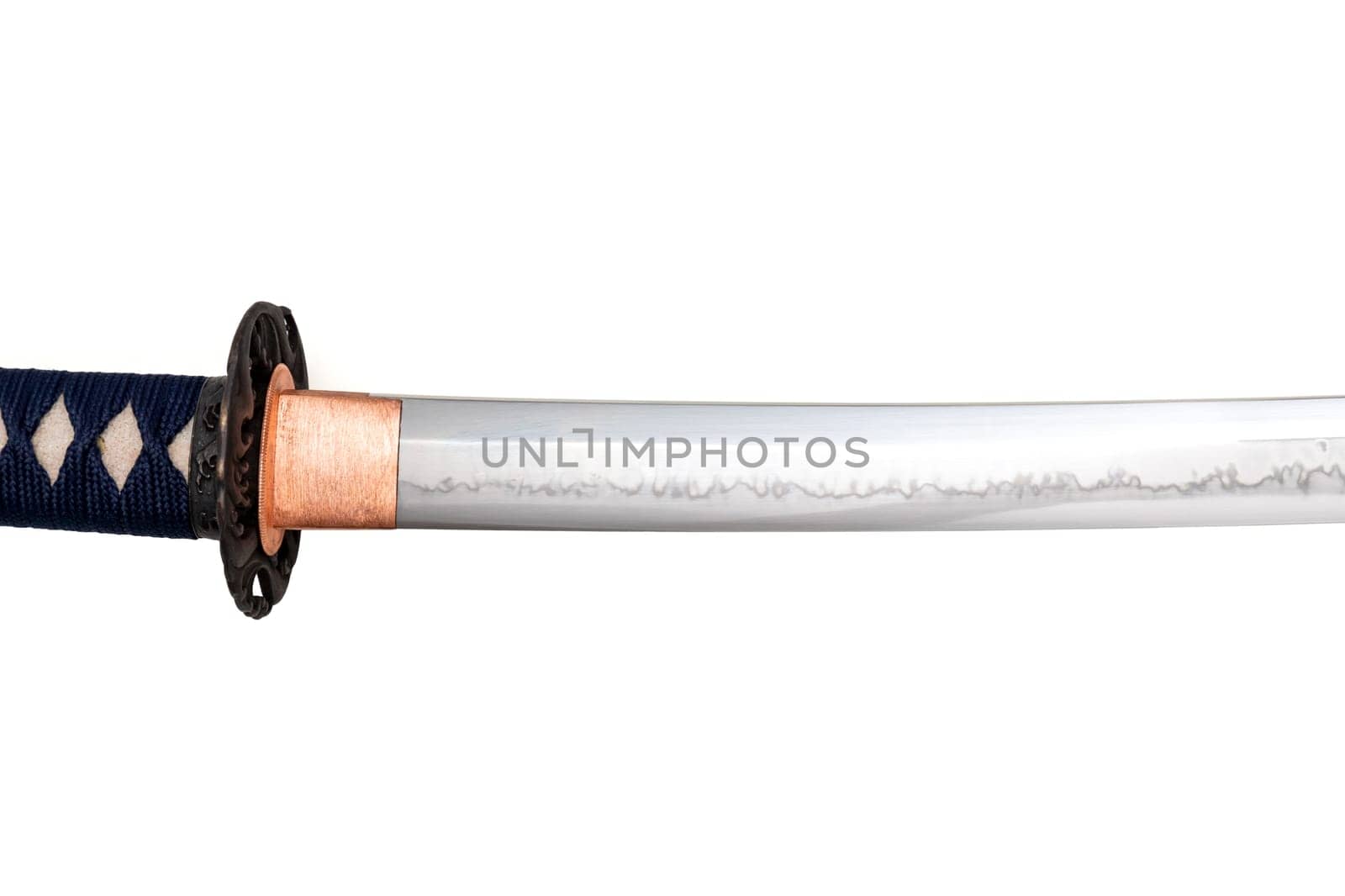 The habaki (collar) is made of polished copper. It is at the base of a Japanese sword blade with a wavy pattern on the sharp part. isolated on a white background. Selective focus.