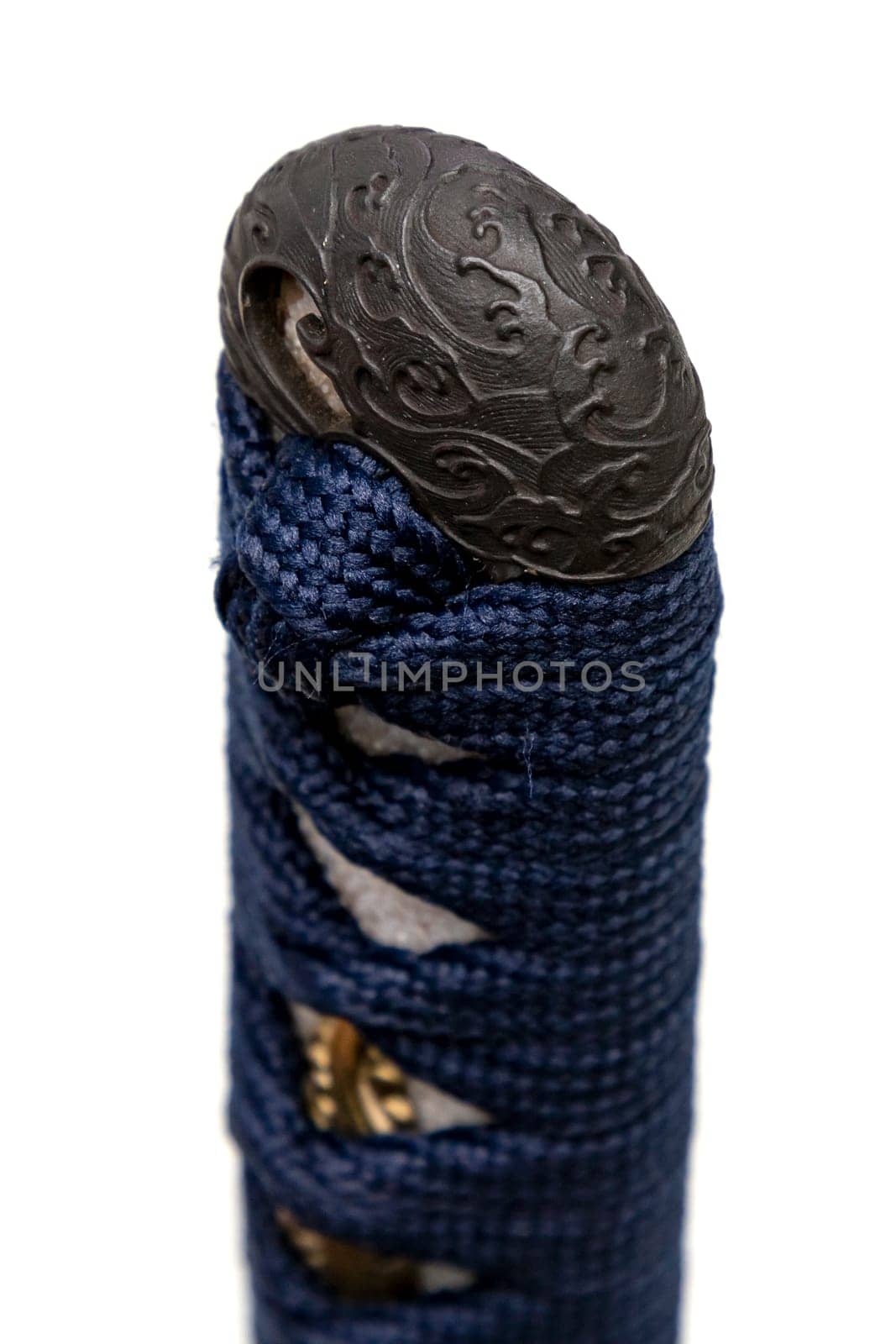 Wave design Kashira : butt cap (or pommel) made of steel on the end of the navy blue silk cord handle Japanese sword isolated in white background. Selective focus.