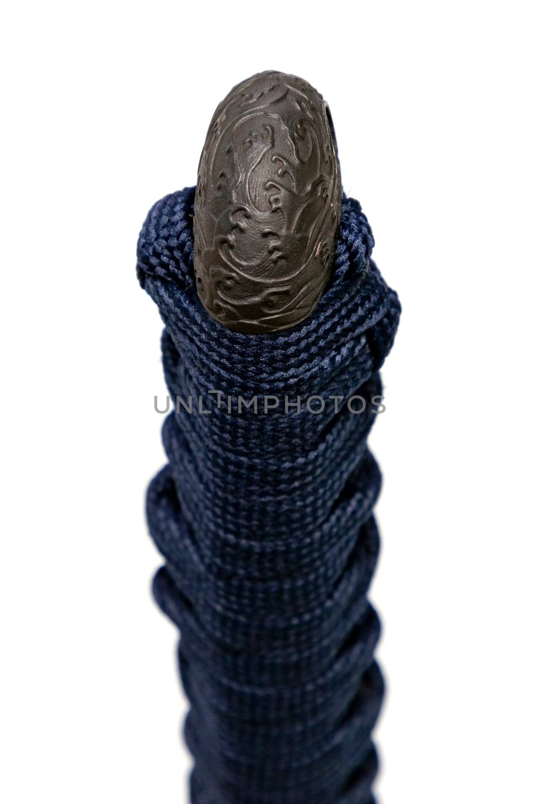Wave design Kashira : butt cap (or pommel) made of steel on the end of the navy blue silk cord handle Japanese sword isolated in white background. Selective focus.