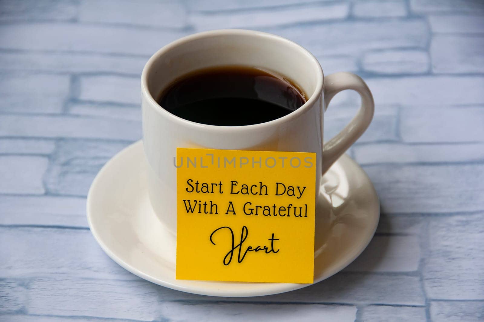 Inspirational quote text on yellow notepad on coffee cup - Start each day with a grateful heart. Motivational concept.