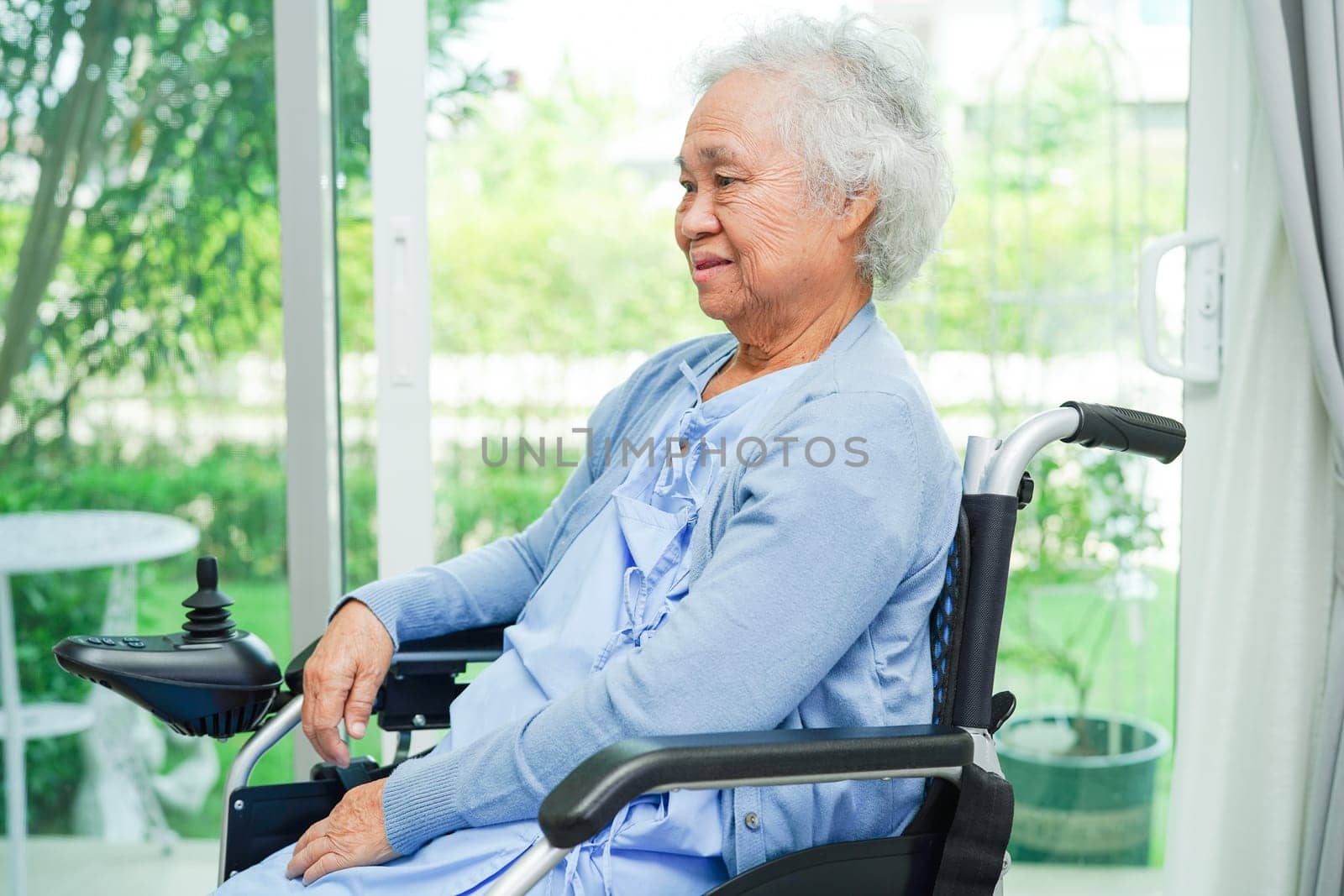 Asian elderly woman disability patient sitting on electric wheelchair in park, medical concept.