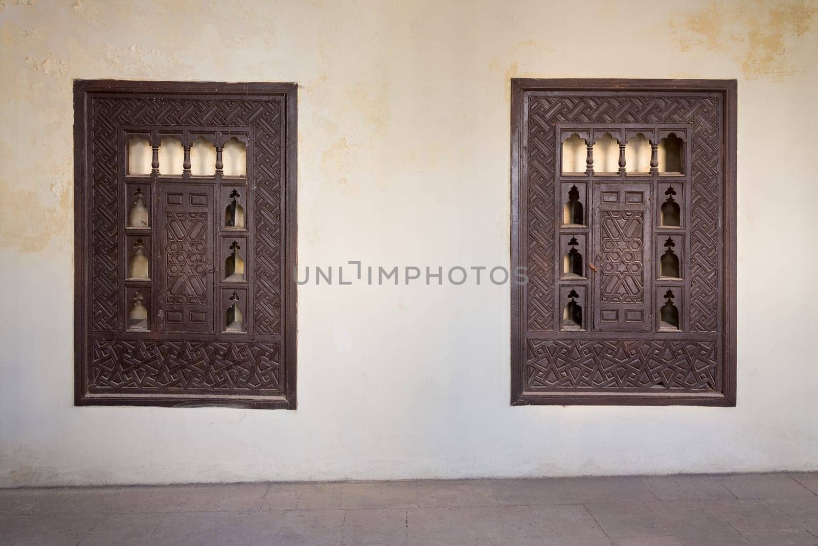 Two wooden arabesque ottoman era cupboards with engraved decorations embedded in a grunge wall