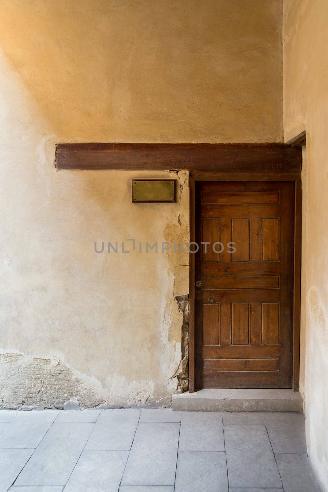 Wooden aged door on grunge stone wall and blank weathered copper door sign, Medieval Cairo, Egypt