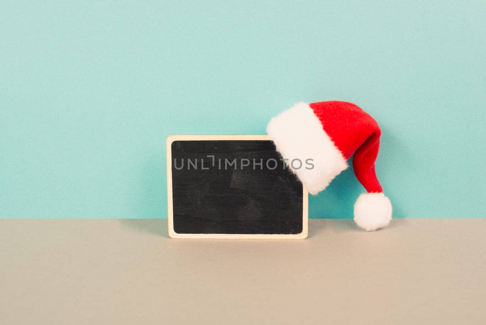 Red Santa Claus hat hanging on a chalkboard, greeting card for christmas, copy space for text, winter season
