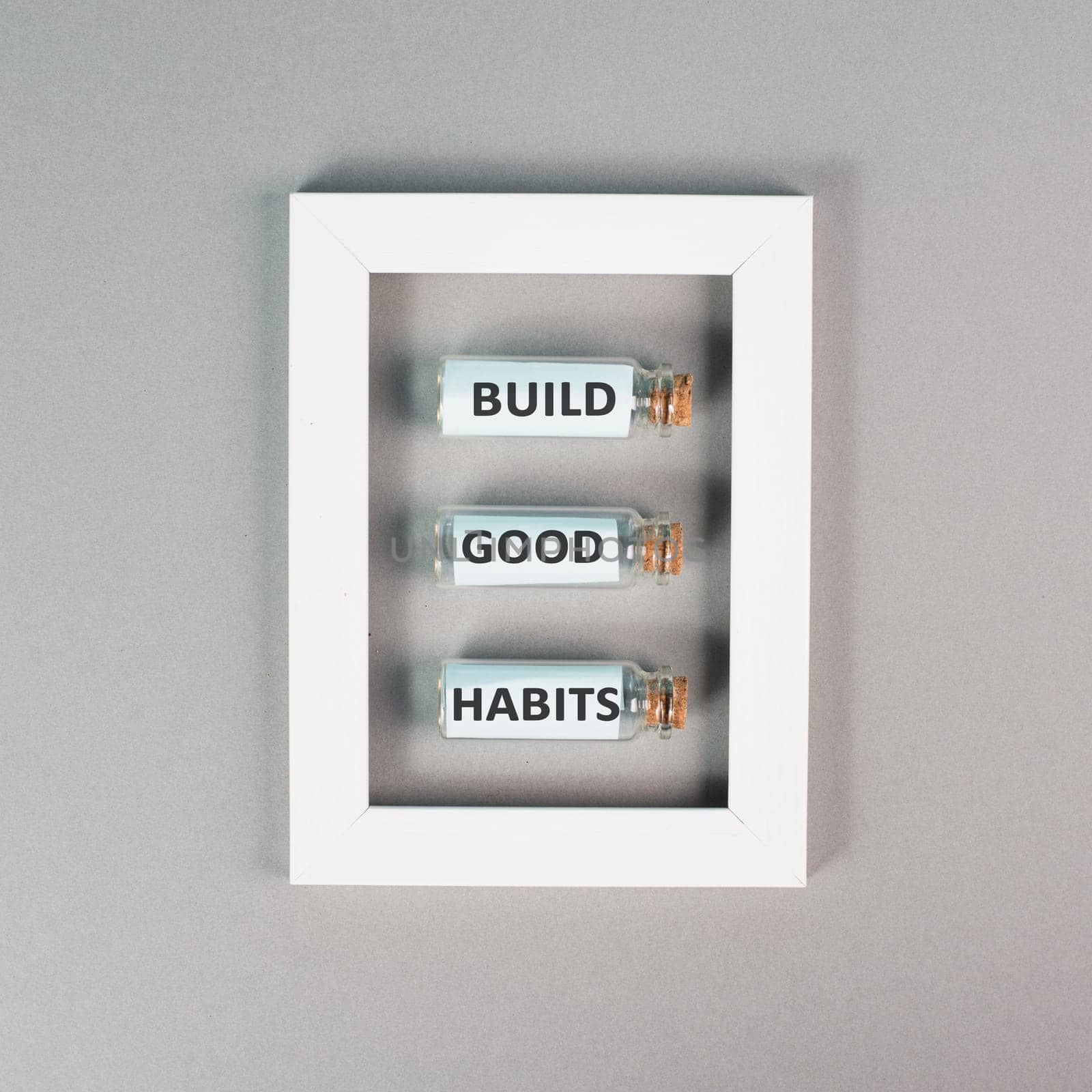 The words build good habits are standing on glass bottles in a frame, change lifestyle, healthy and positive attidude, motivation concept