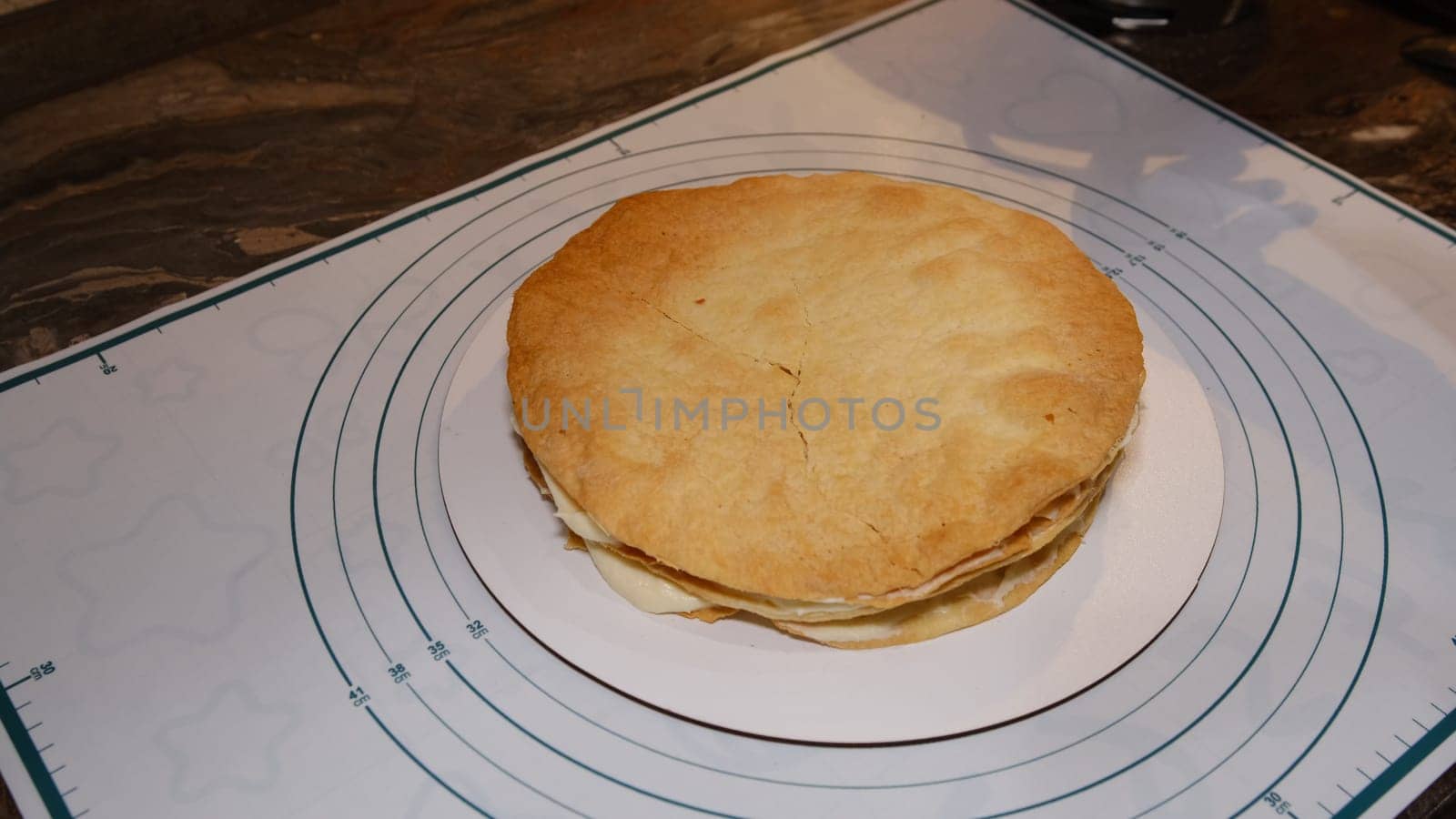 Man's hand levels cream on cake, cake decor. Making Napoleon cake with cream.