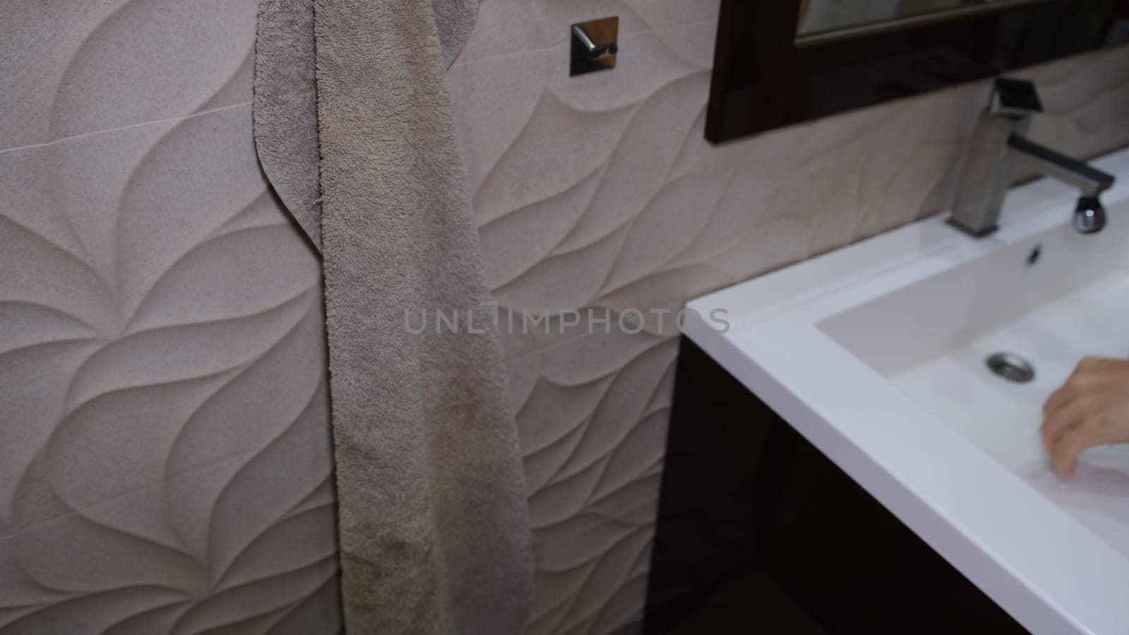 A man drying his hands in the bathroom after washing them with soap to avoid getting infected with coronavirus. Covid concept