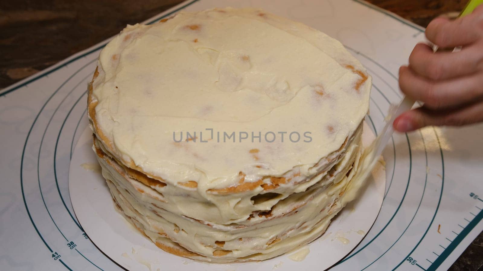 Man's hand levels cream on cake, cake decor. Making Napoleon cake with cream.
