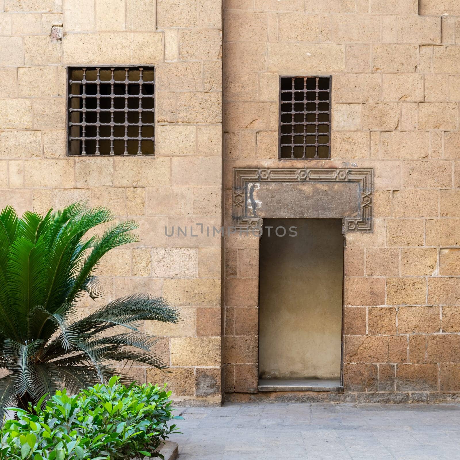 Ancient external old decorated bricks stone wall with two windows and opened door leading to Ottoman era Beit El Sehemy historical building, Cairo, Egypt
