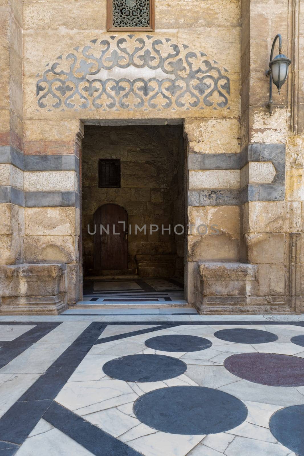 Stone bricks wall and opened door leading to passage at the courtyard of public historic mosque of Sultan Barquq, Moez Street, Old Cairo, Egypt