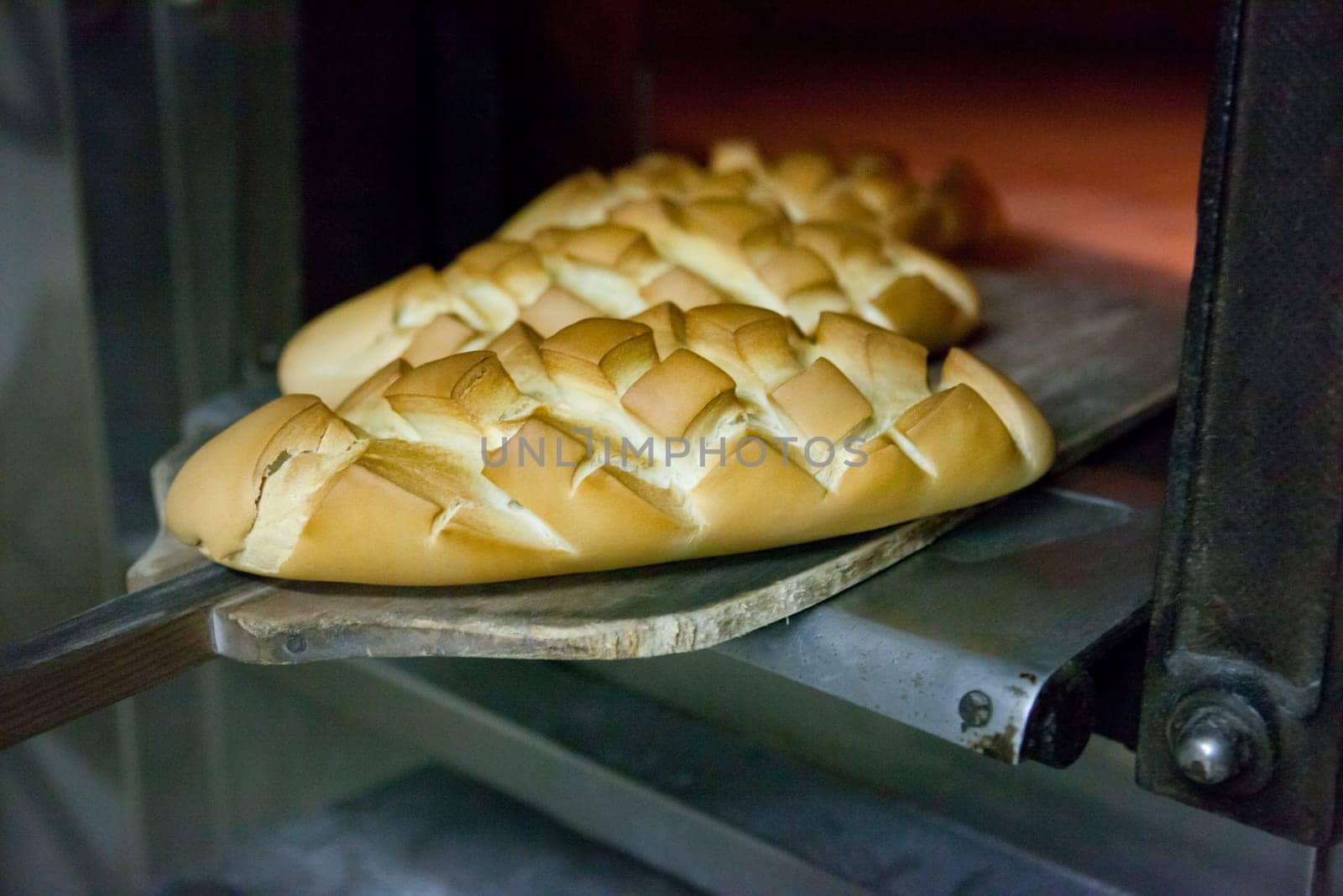 baking peel taking fresh baked bread from oven. Manufacturing process of spanish bread