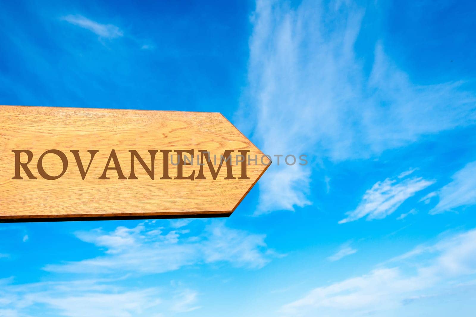 Wooden arrow sign pointing destination ROVANIEMI, FINLAND against clear blue sky with copy space available. Travel destination conceptual image
