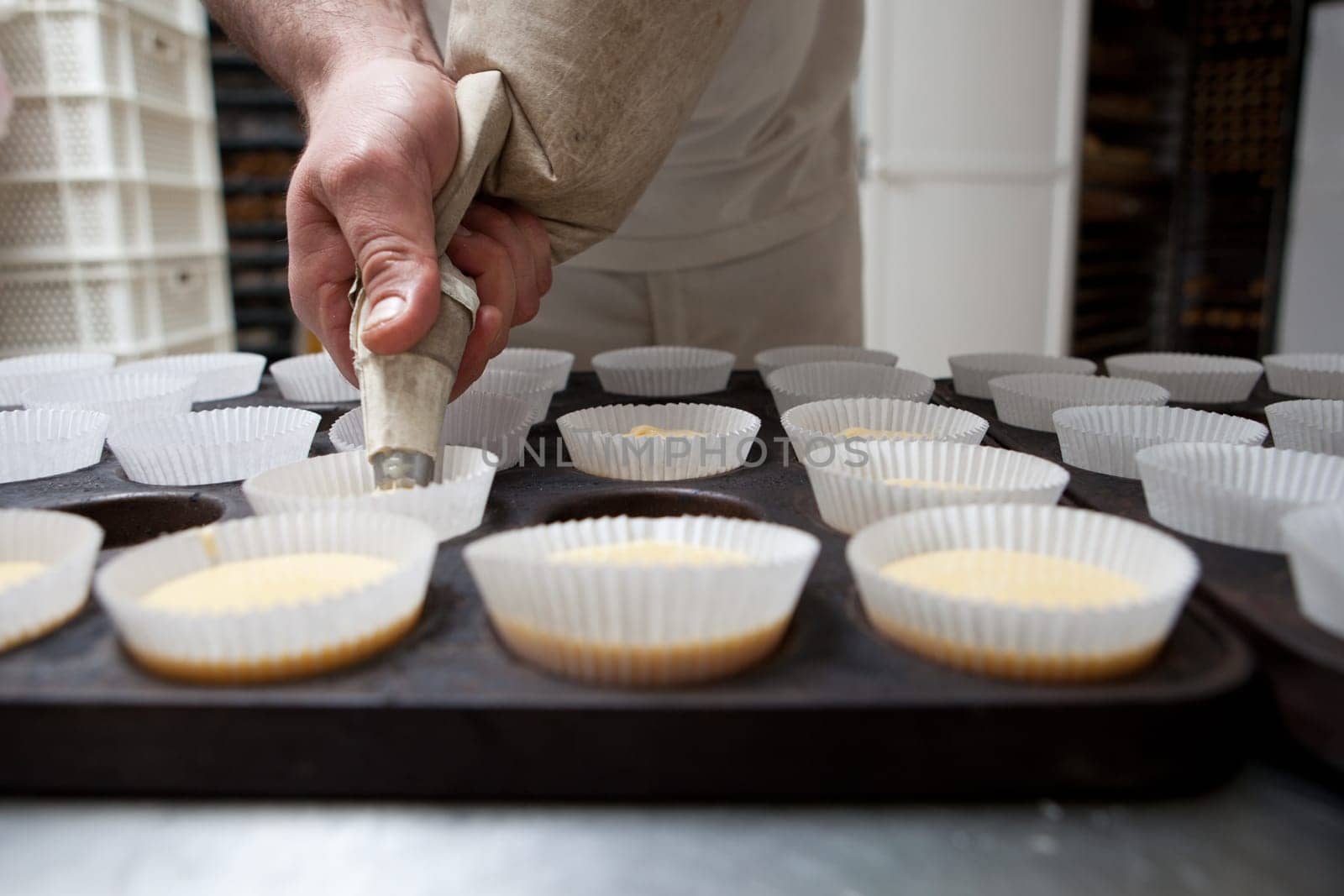 Baking cups being piped. Handmade manufacturing process of spanish madeleines