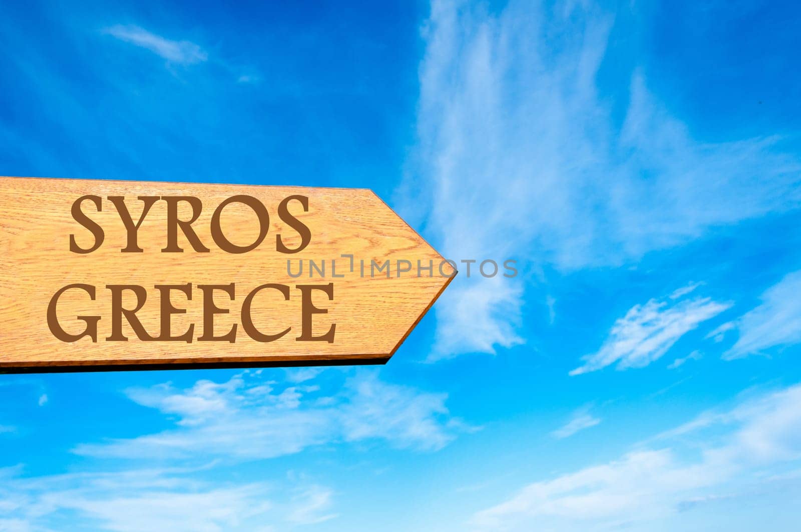 Wooden arrow sign pointing destination SYROS, GREECE against clear blue sky with copy space available. Travel destination conceptual image