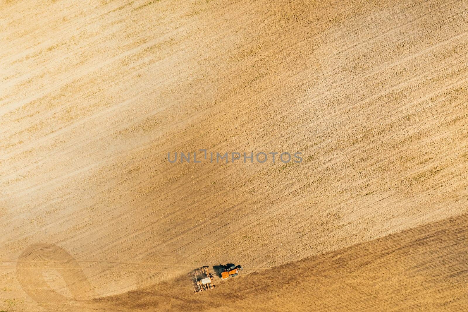 Aerial View. Tractor With Seed Drill Machine Sowing The Seeds For Crops In Spring Season. Beginning Of Agricultural Spring Season. Countryside Field Landscape. Natural Rural Background.