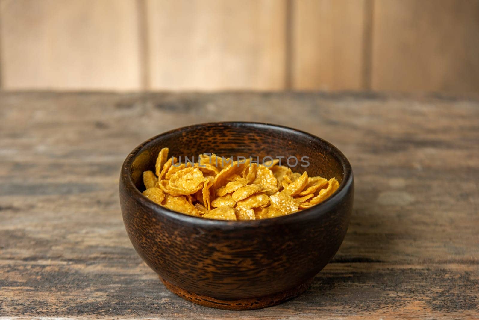 Cereal in wooden bowl with milk splash on blurred wooden background