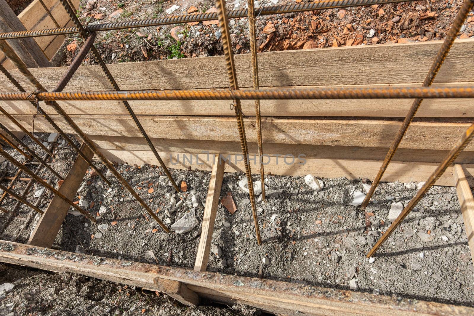 Reinforcement covered with earth during the collapse of the formwork during the installation of strip foundation reinforcement