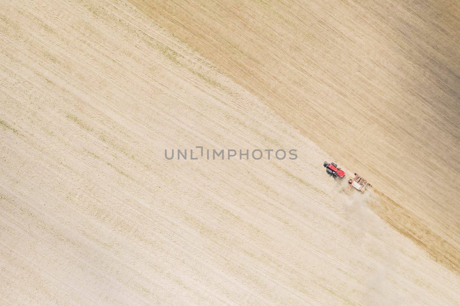 Aerial View. Tractor With Seed Drill Machine Sowing The Seeds For Crops In Spring Season. Beginning Of Agricultural Spring Season. Countryside Field Landscape. Natural Rural Background.
