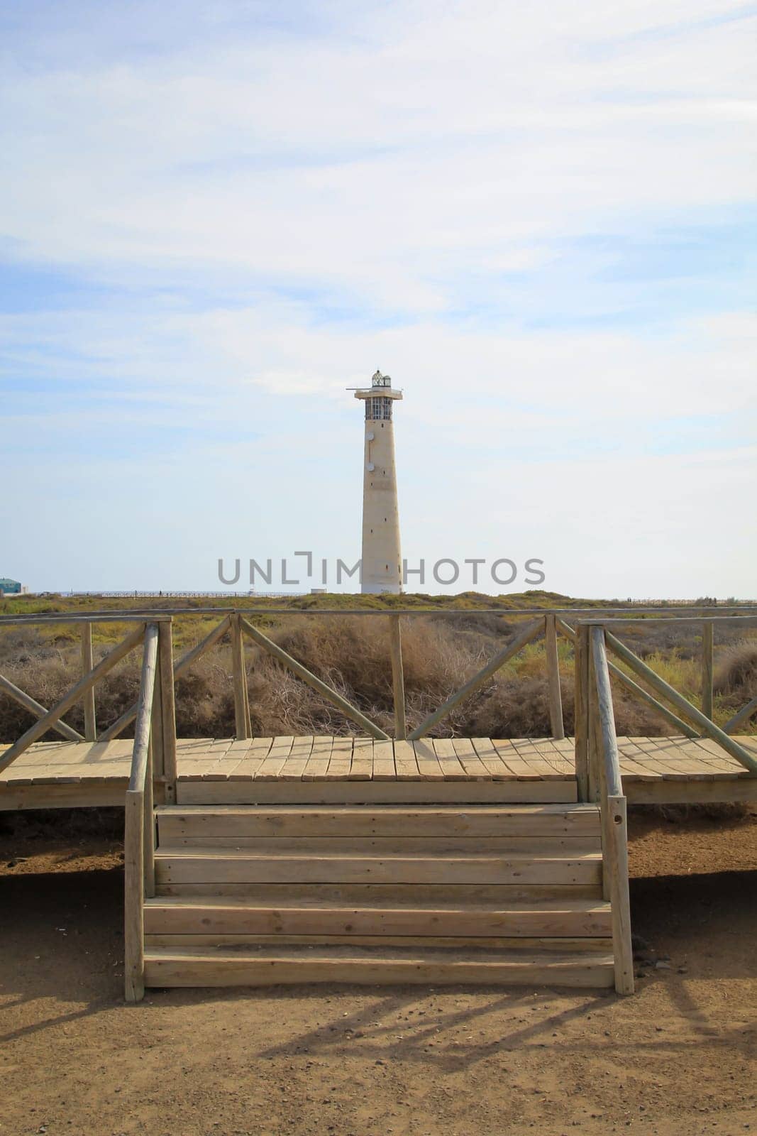 View of a lighthouse standing in the background of the dunes.