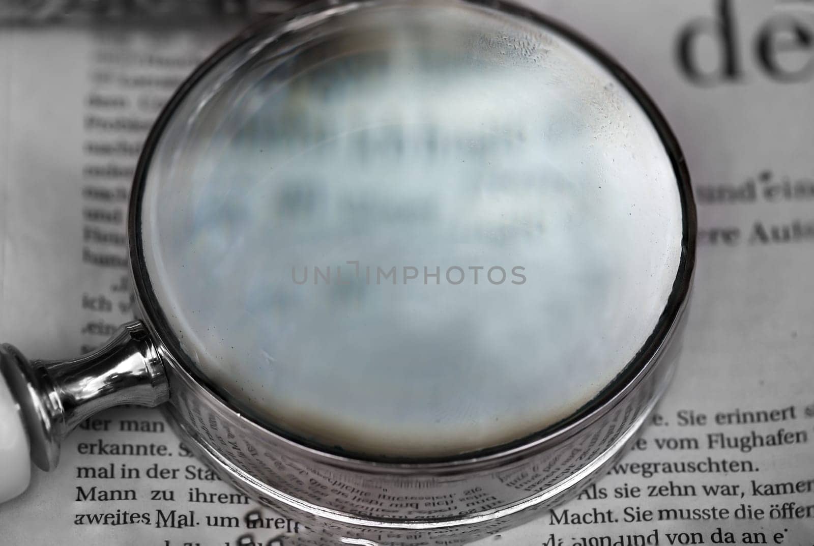 A magnifying glass, a reading aid lies on an old newspaper.