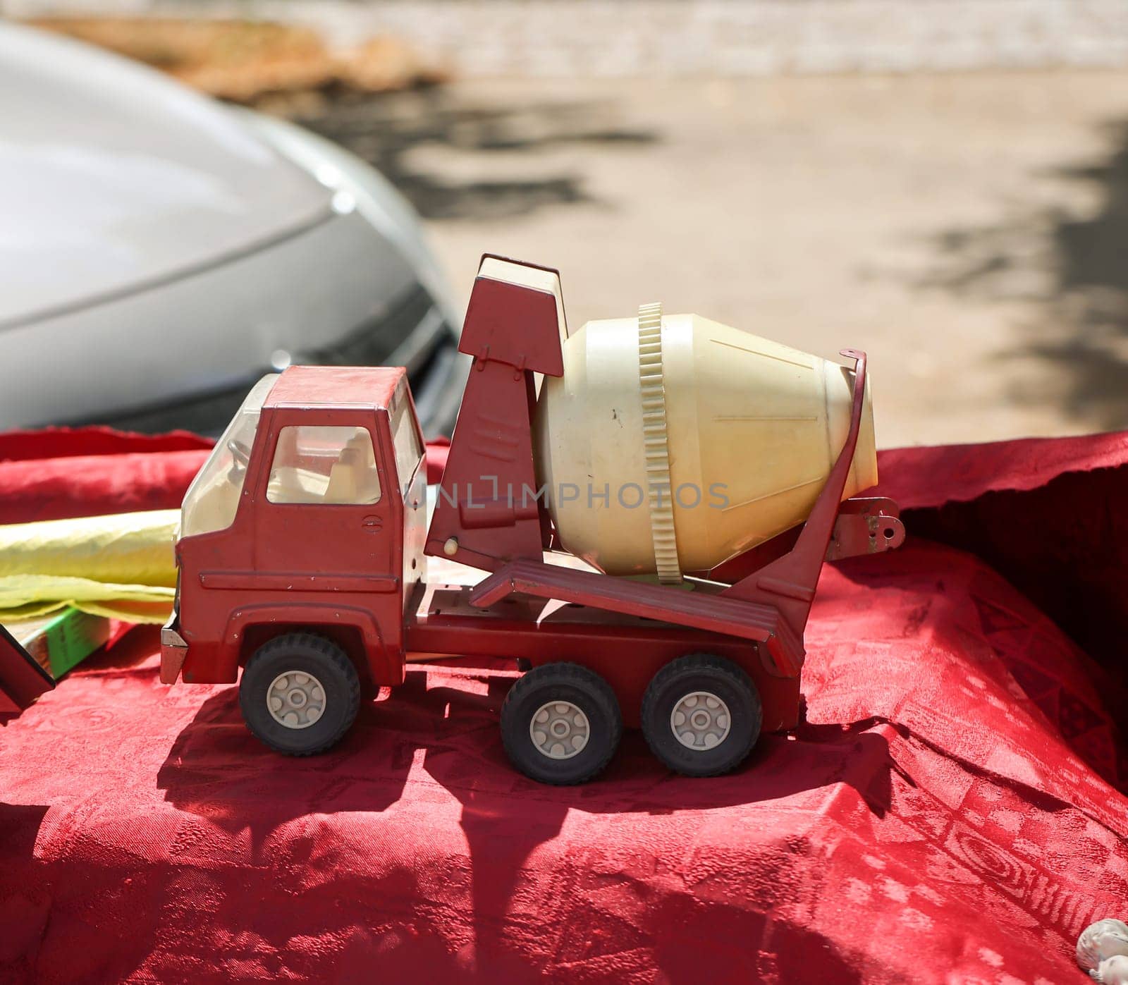 On a table is a red and yellow toy car, a concrete mixer truck. Toys for children.