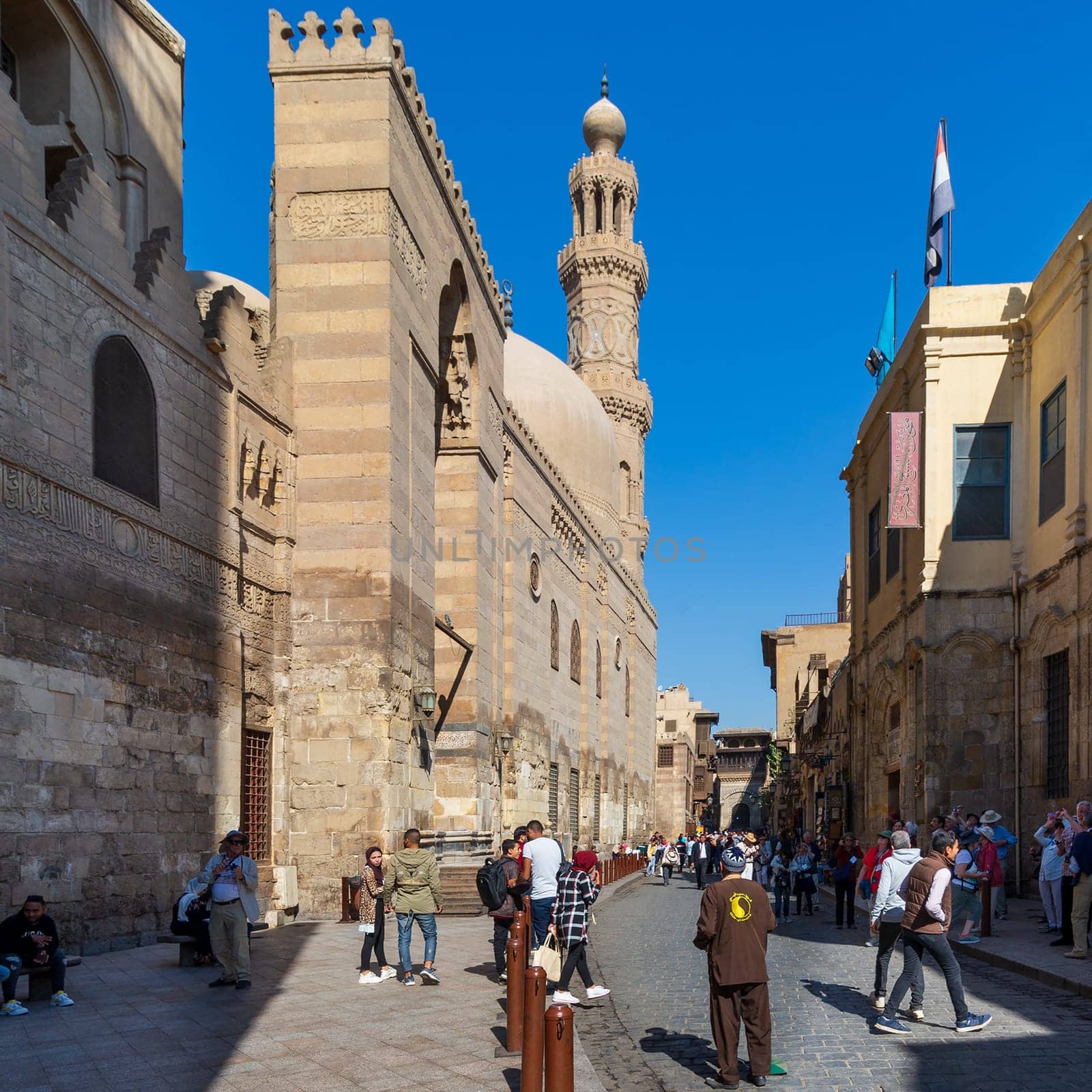 Cairo, Egypt- November 23 2019: Moez Street with local visitors, Minaret of Sultan Barquq Mosque, and Sabil-Kuttab of Katkhuda historic building at the far end, Gamalia district, Old Cairo