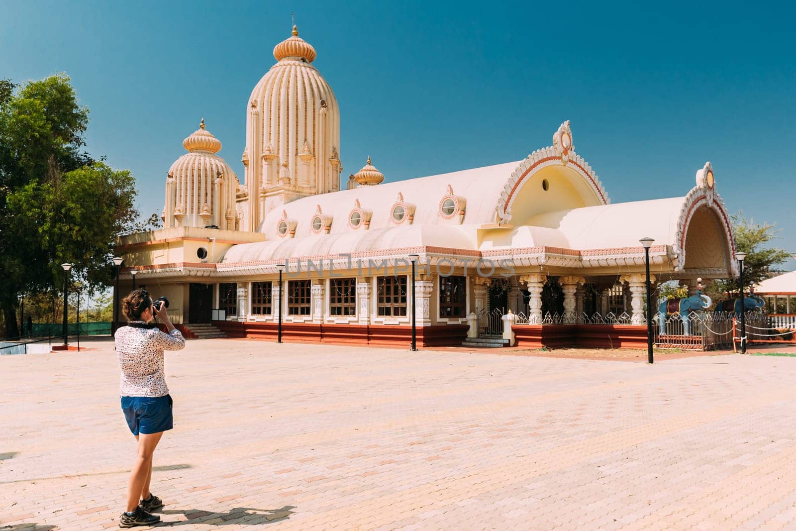 Mapusa, Goa, India. Young Woman Tourist Lady Photograph Taking Pictures Near Shree Ganesh Mandir, Ganeshpuri Temple. Famous Landmark And Popular Destination.