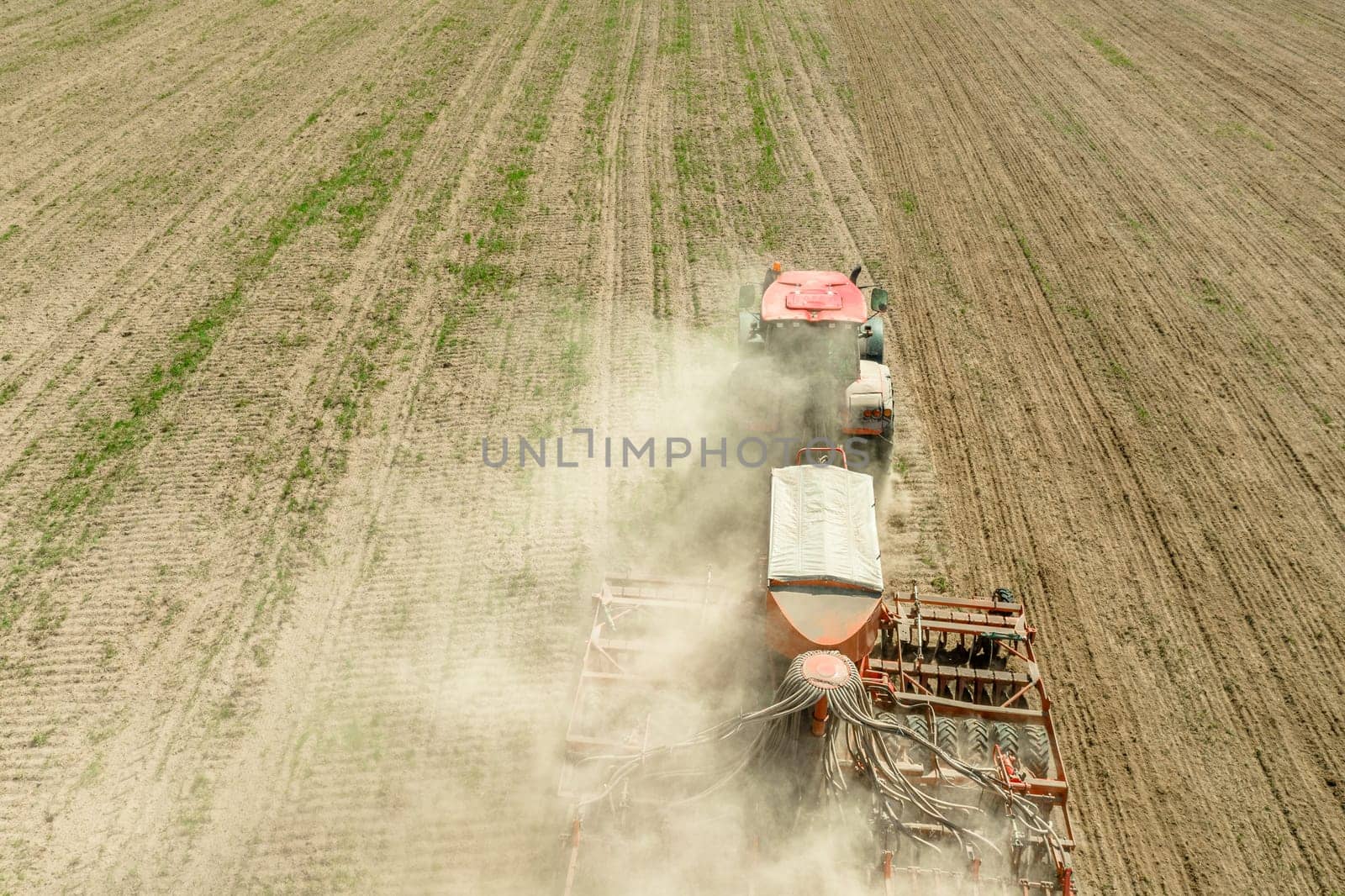 Aerial View. Tractor With Seed Drill Machine Sowing The Seeds For Crops In Spring Season. Beginning Of Agricultural Spring Season. Countryside Rural Field Landscape.