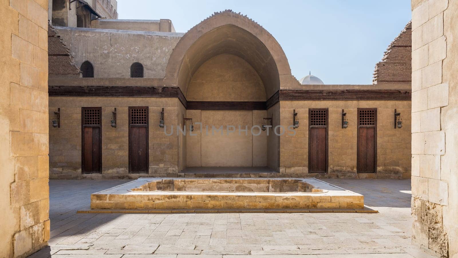 Courtyard of public historic mosque of Sultan Al Nassir Qalawun with side arched iwan and closed wooden doors, Cairo, Egypt