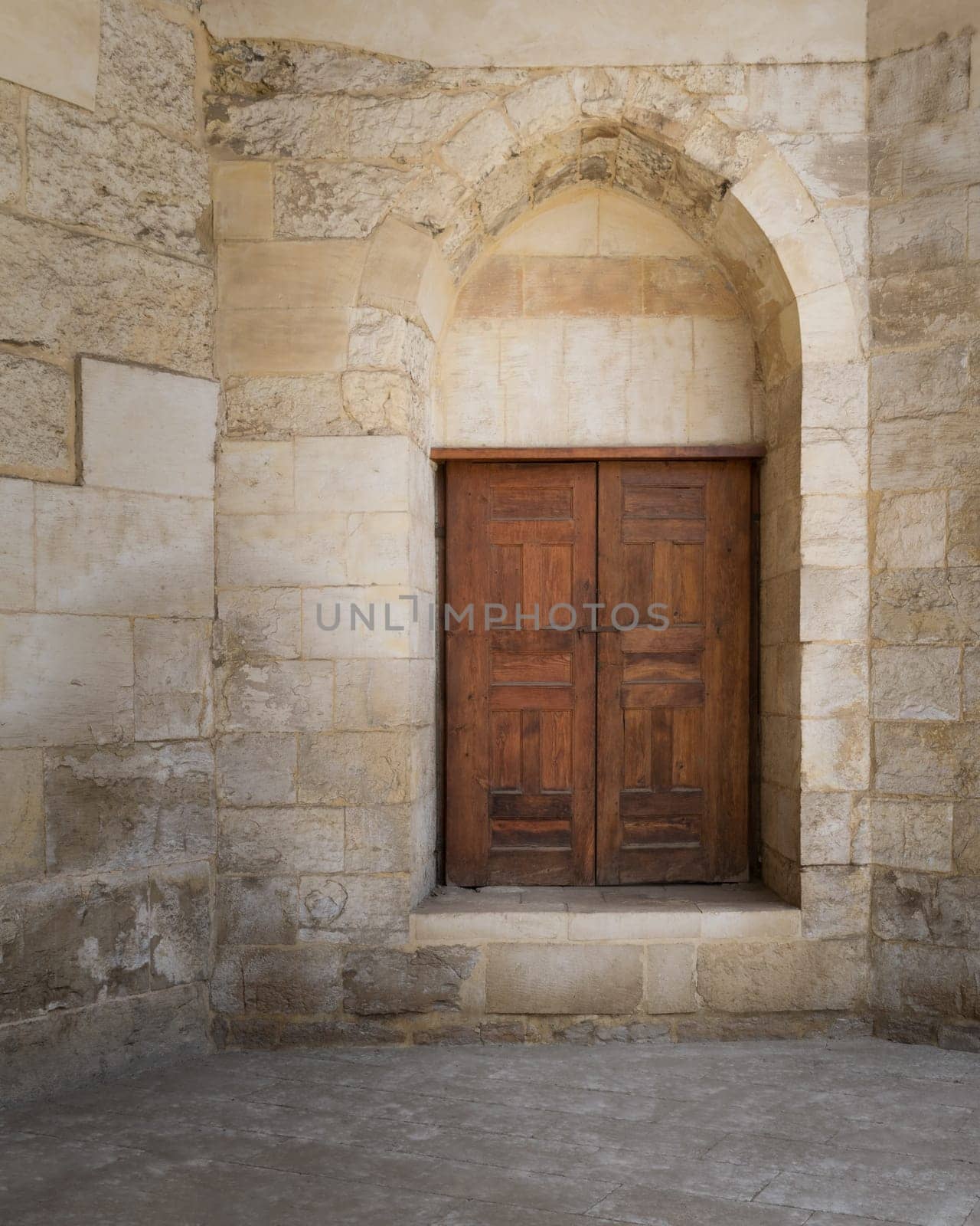 Vaulted closed decorated wooden grunge door in bricks stone wall at public historic Amir Aqsunqur Mosque, Blue Mosque, Cairo, Egypt