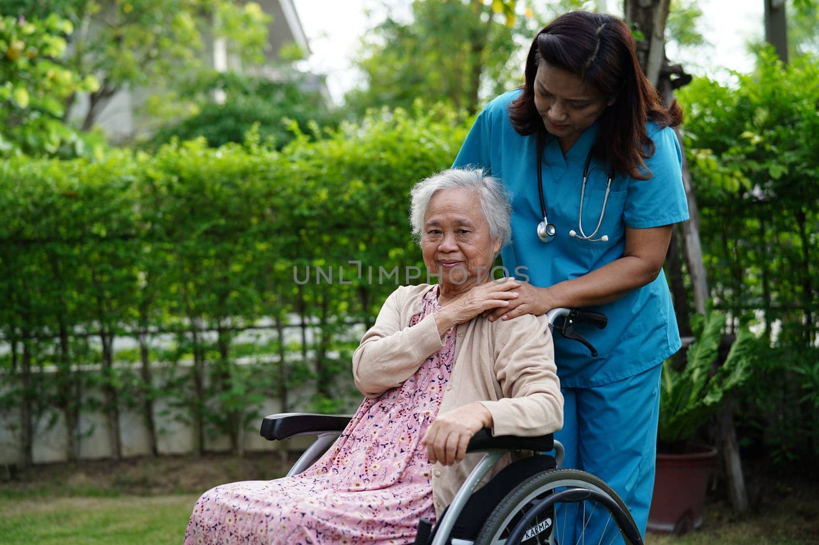 Doctor help Asian elderly woman disability patient sitting on wheelchair in park, medical concept.