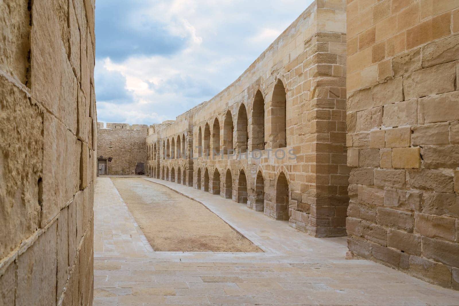 Aged building of stone blocks with archs and windows on cloudy day