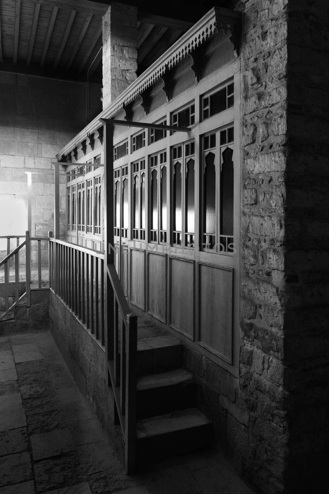 Black and white weathered porch of aged ornamental building at dark night