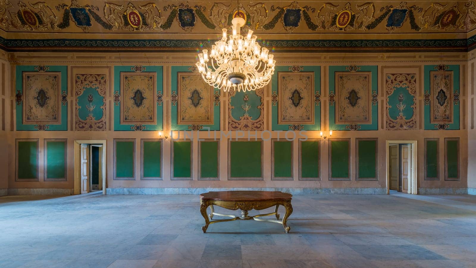 Royal era historic Manasterly Palace with beautiful elegant carved frames on green wall with ornate borders, floral decorated ceiling, chandelier, and marble floor, Cairo, Egypt