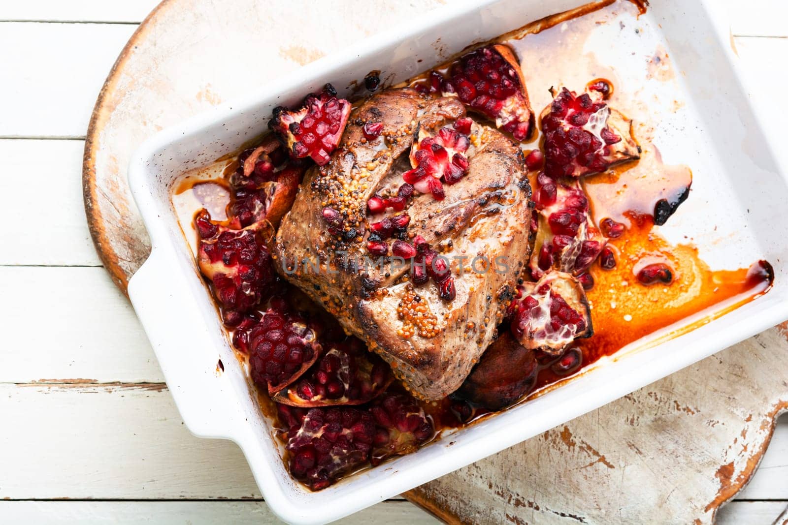 Piece of meat fried with pomegranate in baking dish