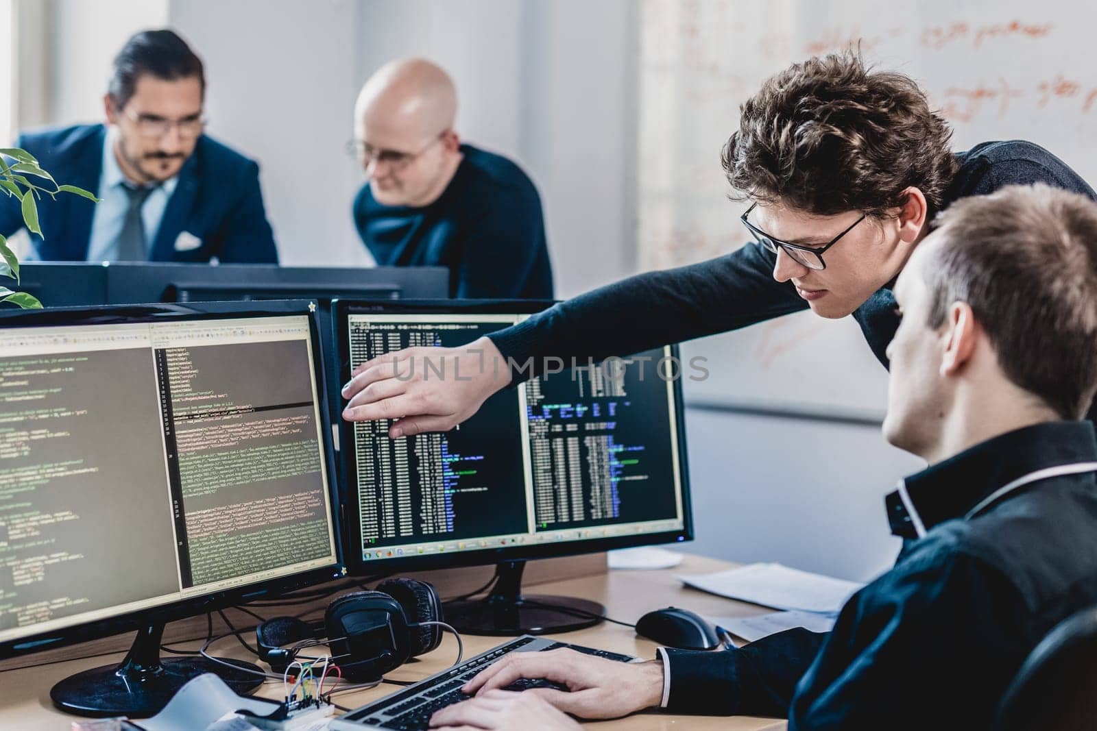 Startup business and entrepreneurship problem solving. Young AI programmers and IT software developers team brainstorming and programming on desktop computer in startup company share office space.