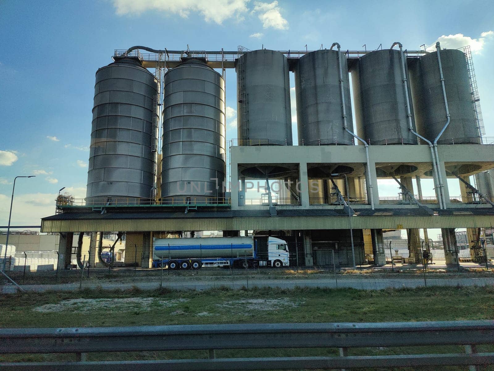 Oil storage tank terminal and tanker, petrol industrial zone shot from a moving car.