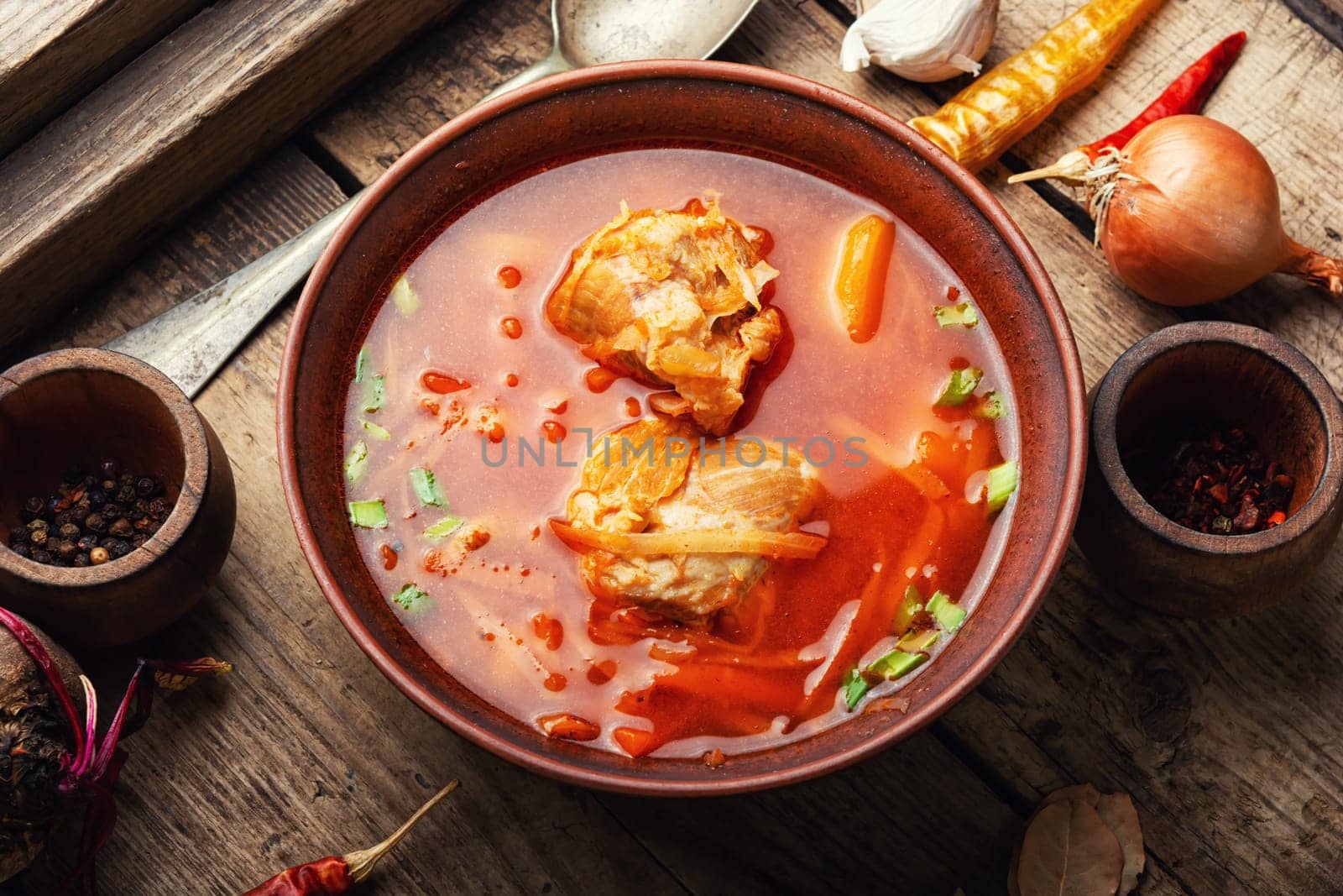 Delicious Ukrainian red borscht in a plate on a rustic old wooden table