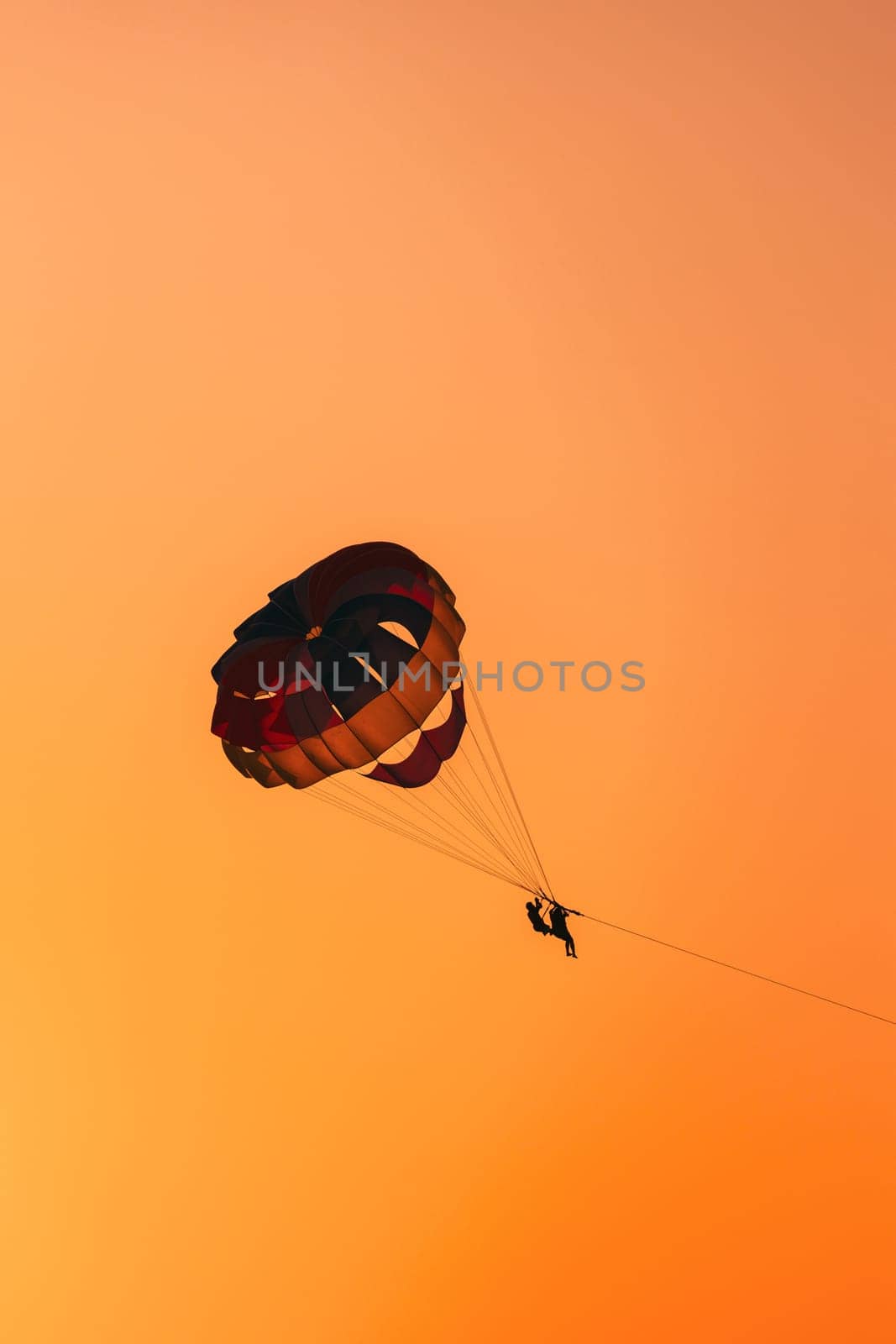 Parasailers Flying On Colorful Parachute In Sunset Sunrise Sky. Active Hobby.