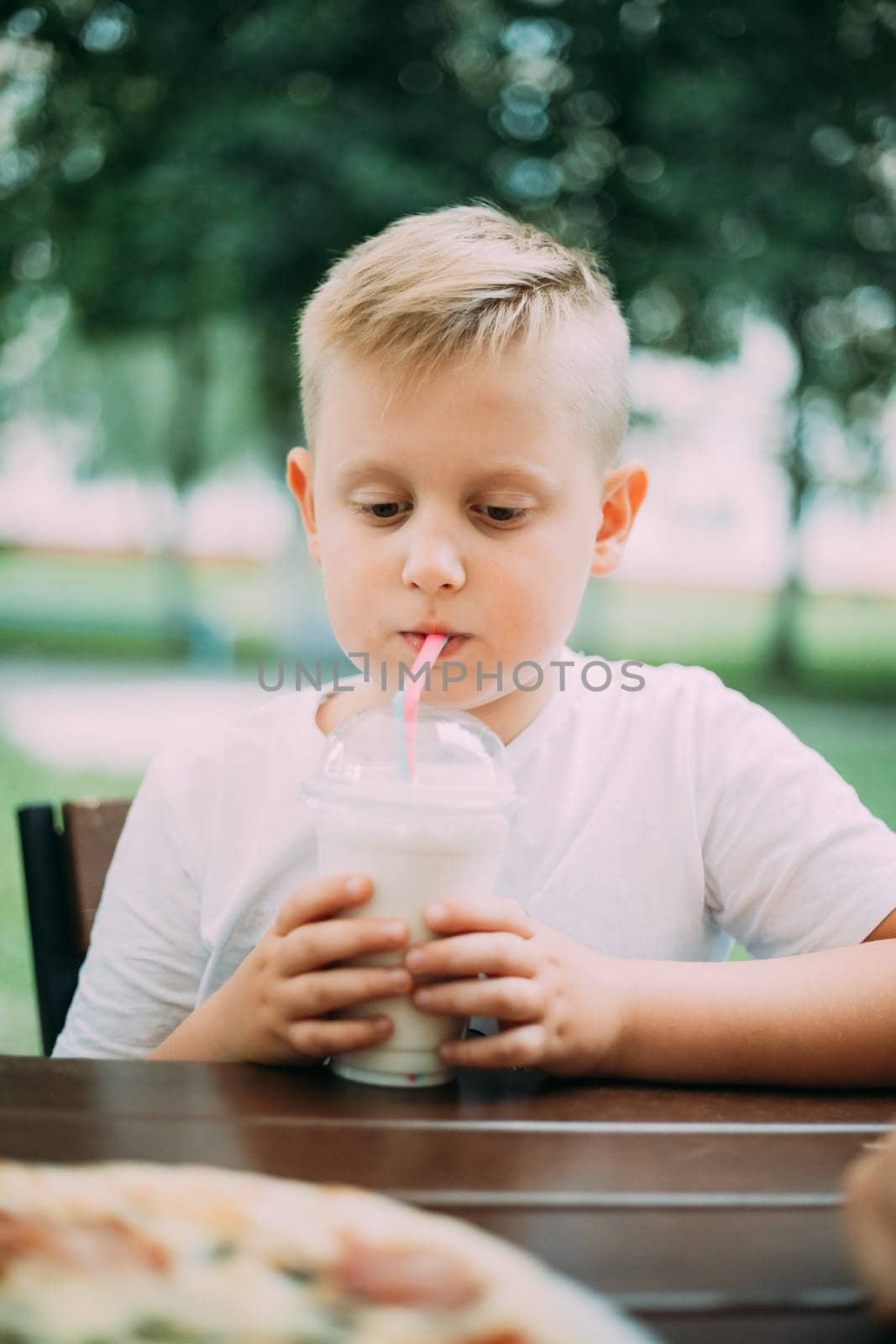 Little Boy Drinking Milkshake In Cafe In Summer Day.