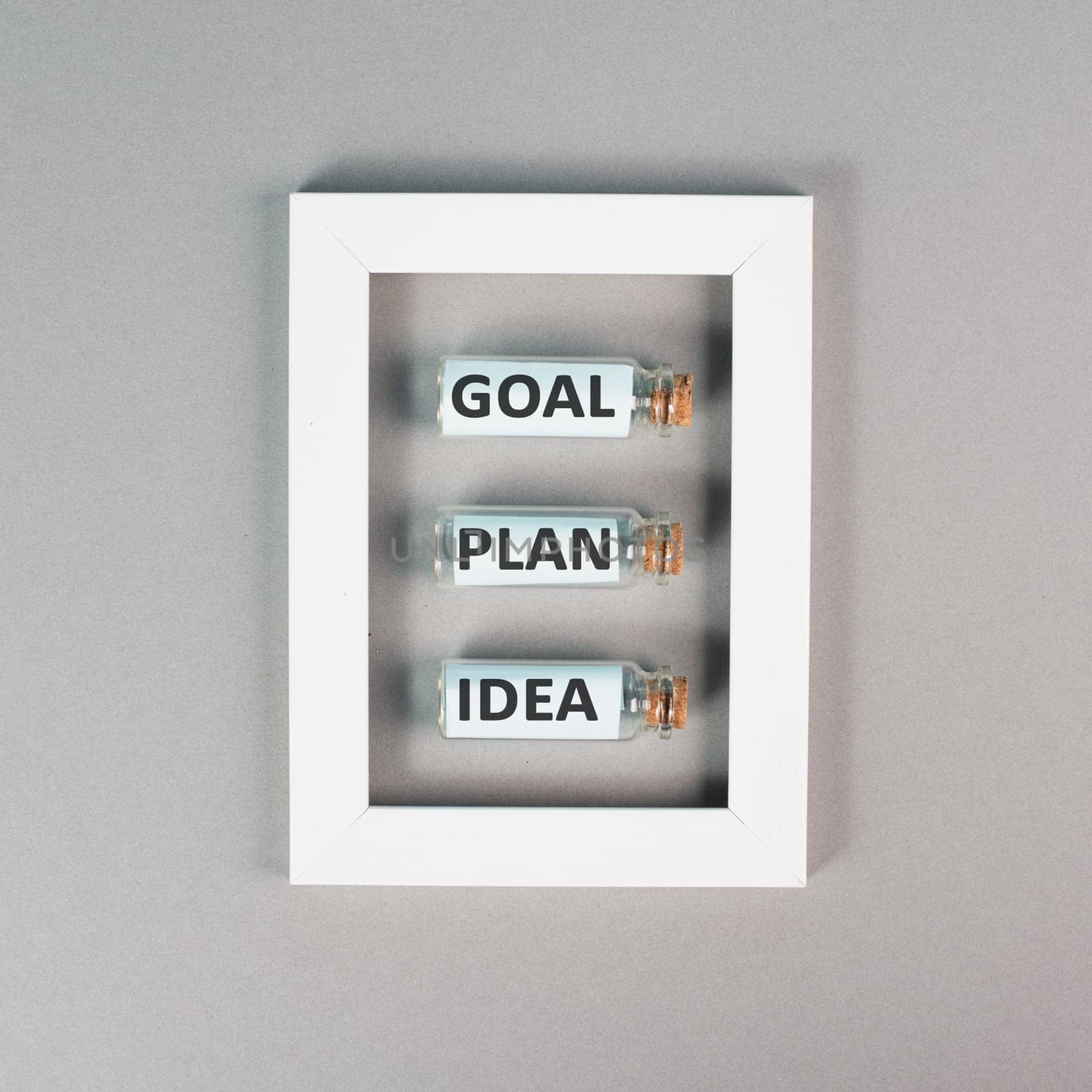 Three glass bottles with the words idea, plan and goal in a frame, education, marketing and business concept, brainstorming for new targets