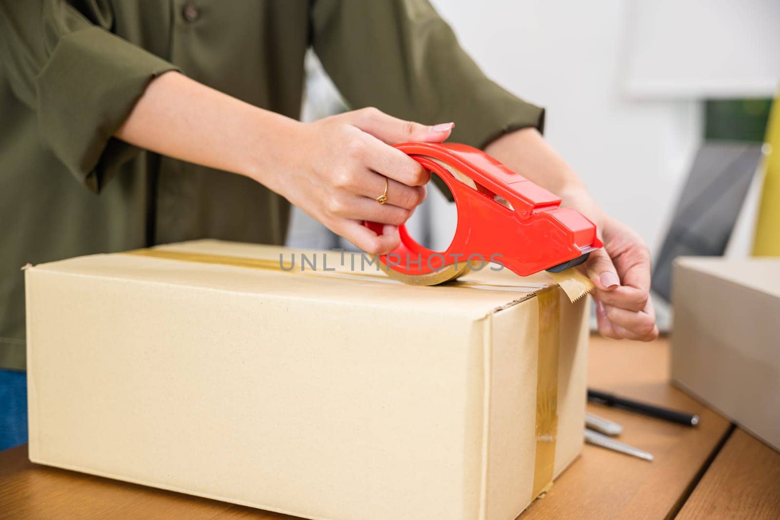 Close up woman hand packing shipment box with transparency tape at home office, happy freelance and packing cardboard box delivery products to customers, Startup small business, Moving day