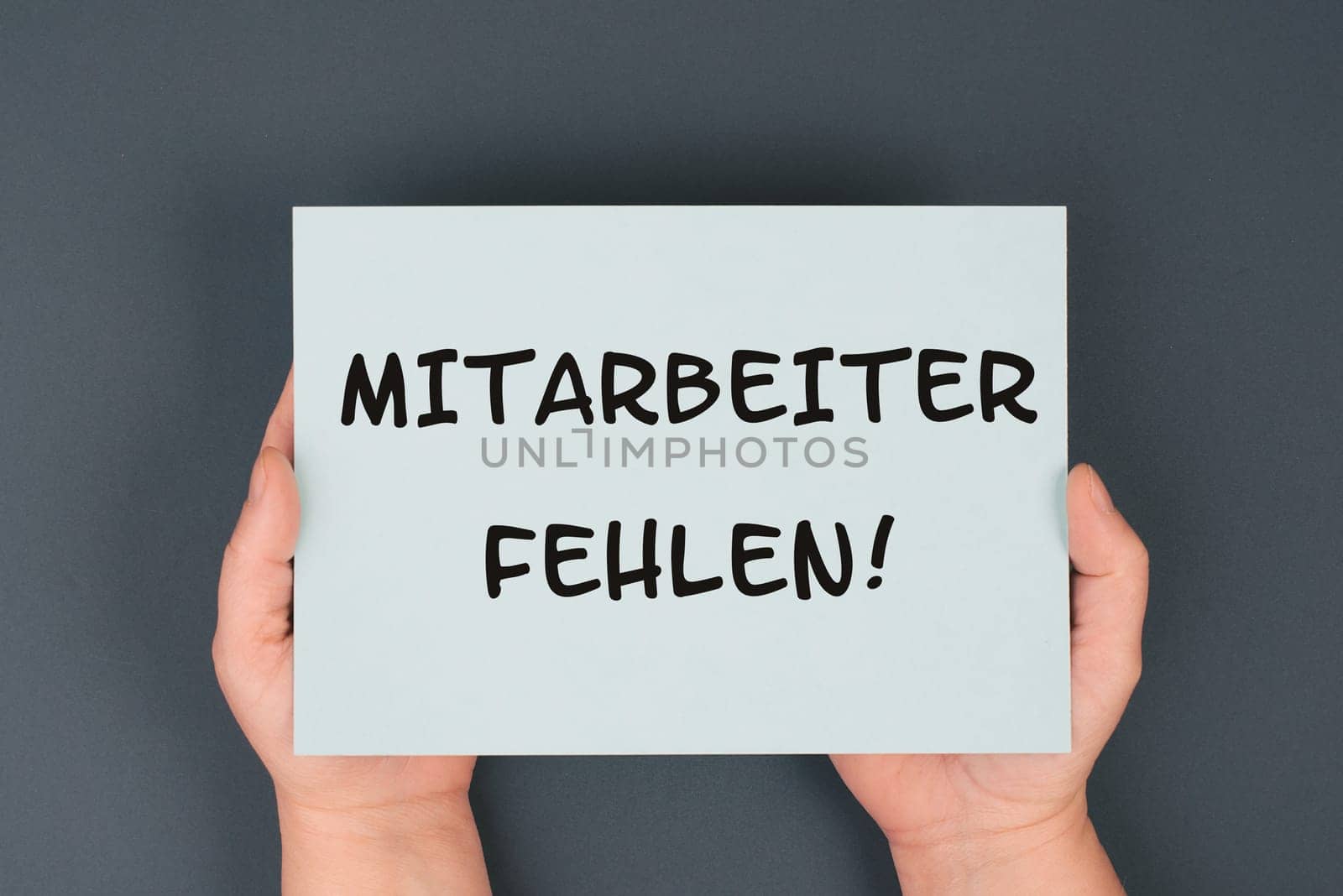 The words shortage of employees are standing in german language on the paper, skilled workers are missing