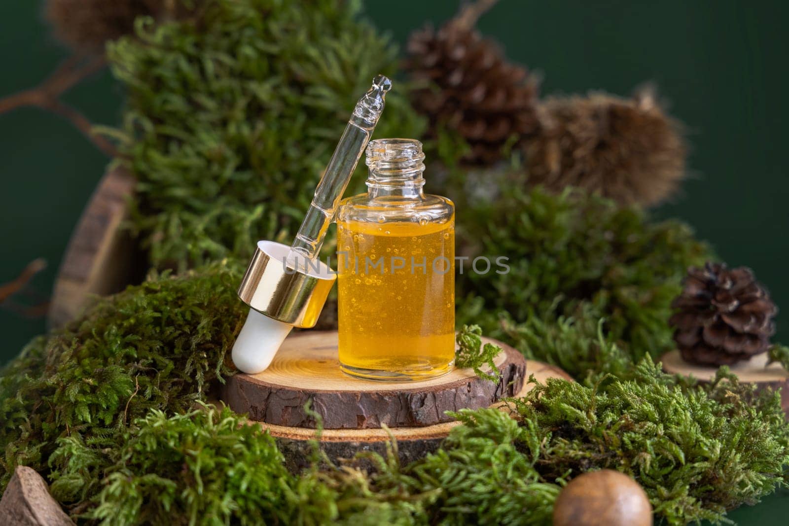 Opened dropper bottle with yellow liquid near green moss, close up. Skincare beauty product, serum or essential oil, natural Organic Cosmetic concept