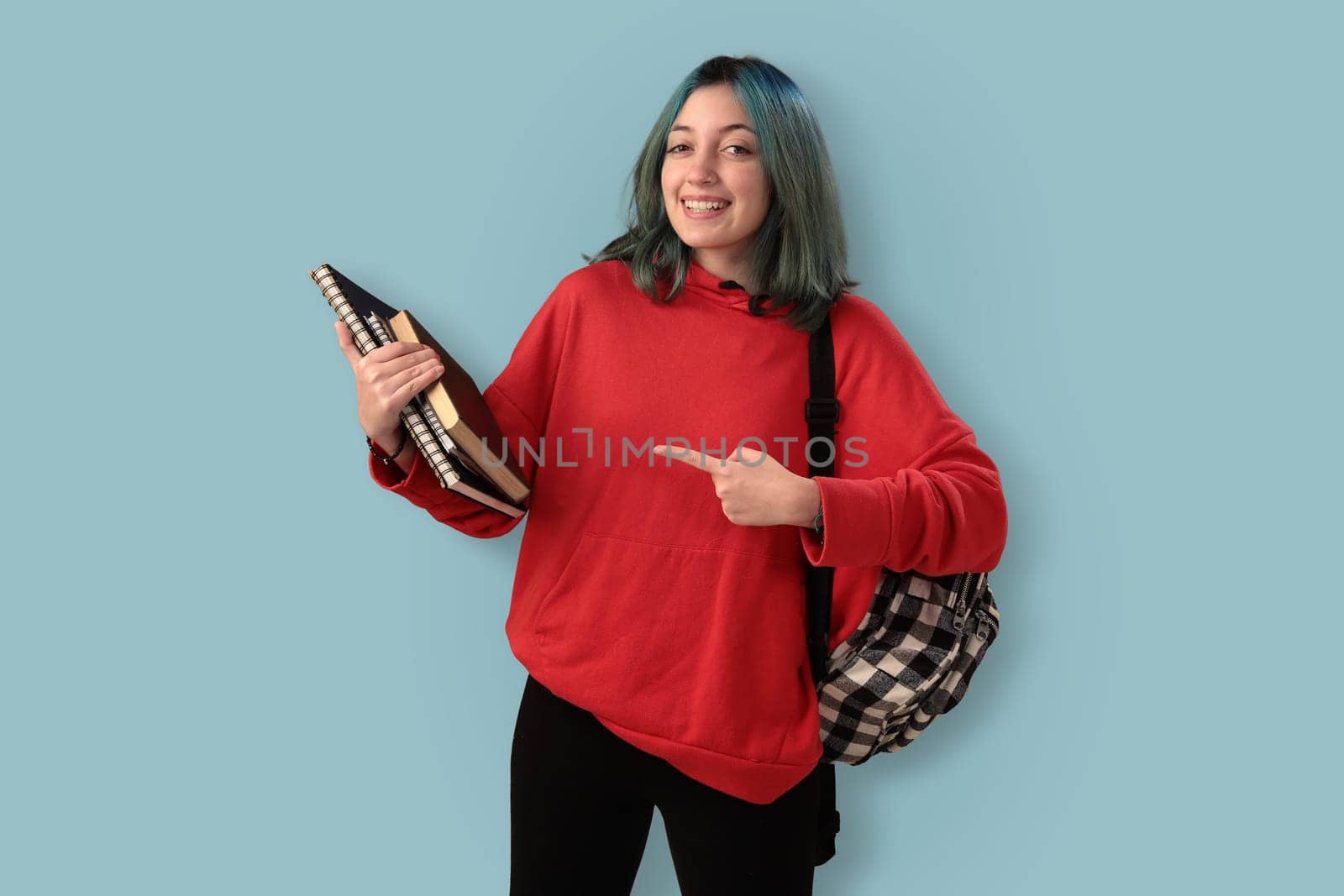 Cute young gilr student with blue hair books and a backpack over a cyan background
