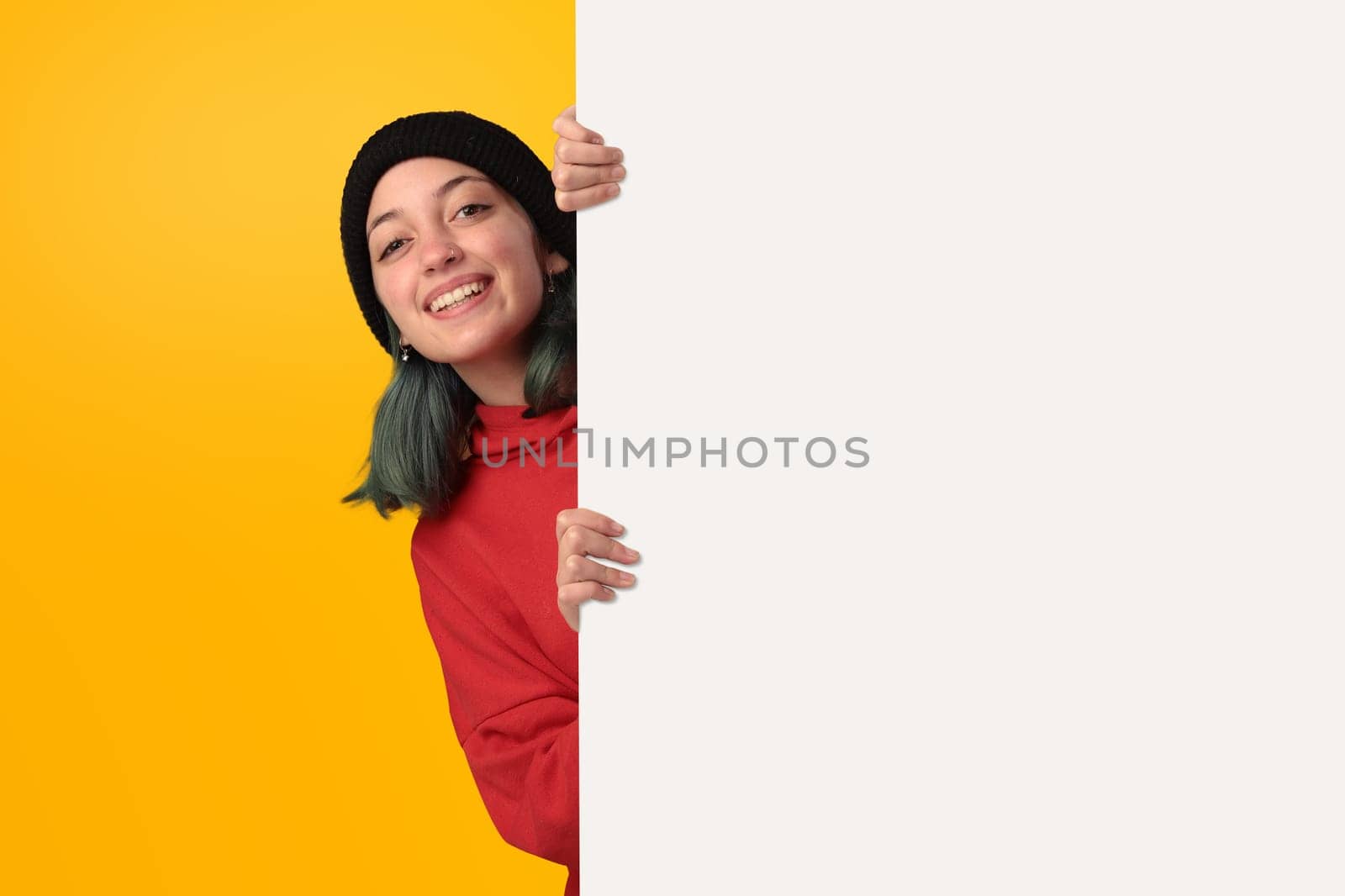 Lovely young girl holding a big blank board over yellow background