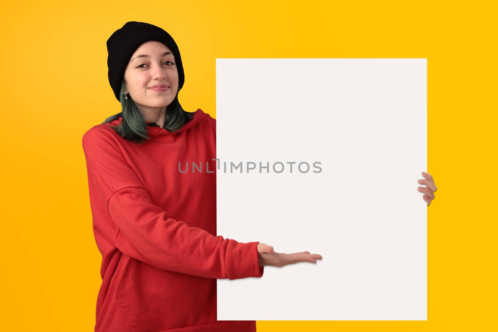 Lovely young girl holding a big blank board over yellow background
