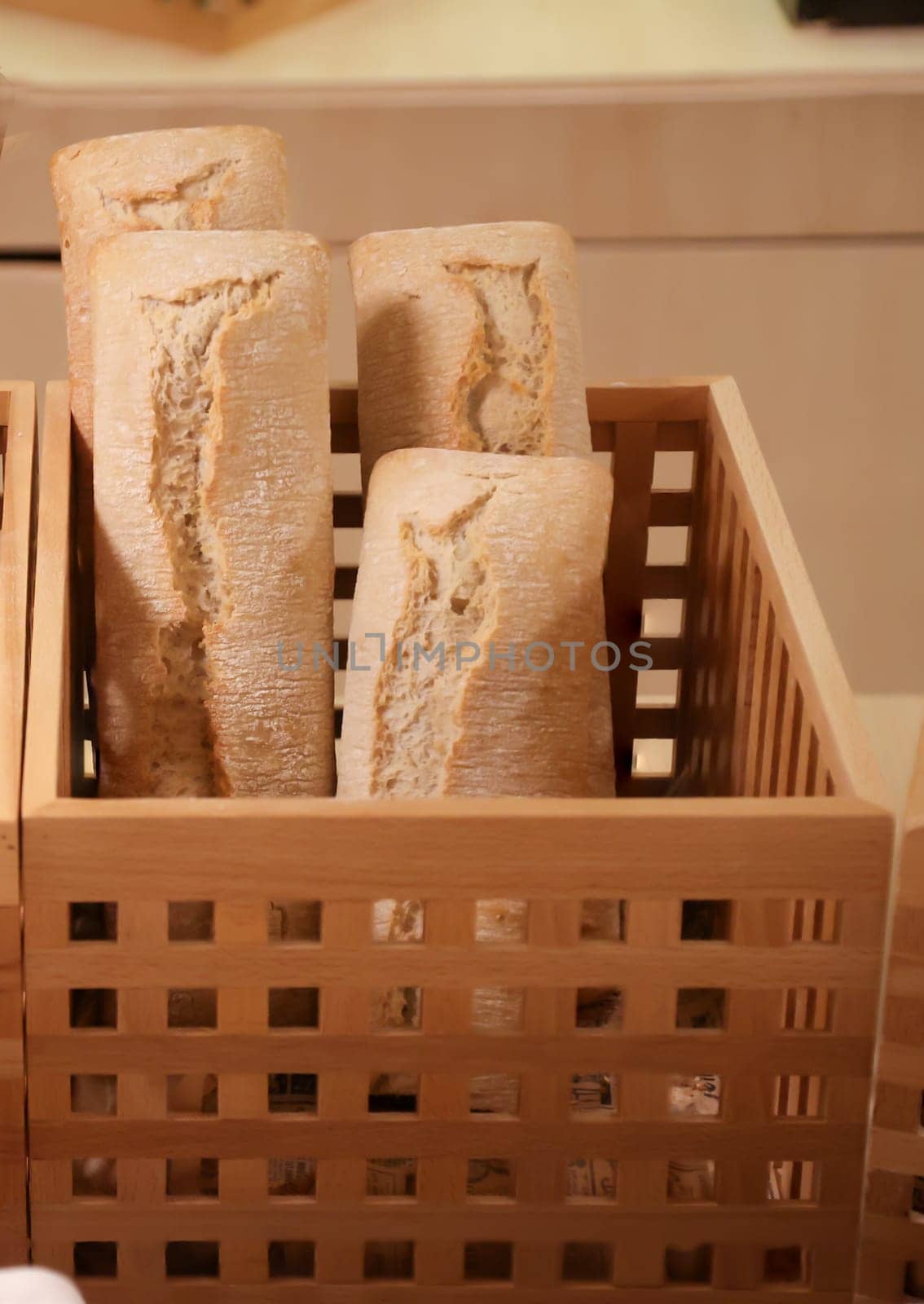 Several loaves of bread, baguettes stand on end in the wooden basket.
