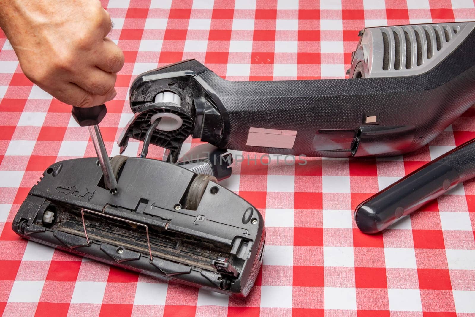 Repair of household appliances. Professional technician repairs a vacuum cleaner. Household appliances customer service. Battery hoover. Repair by a specialist on site.