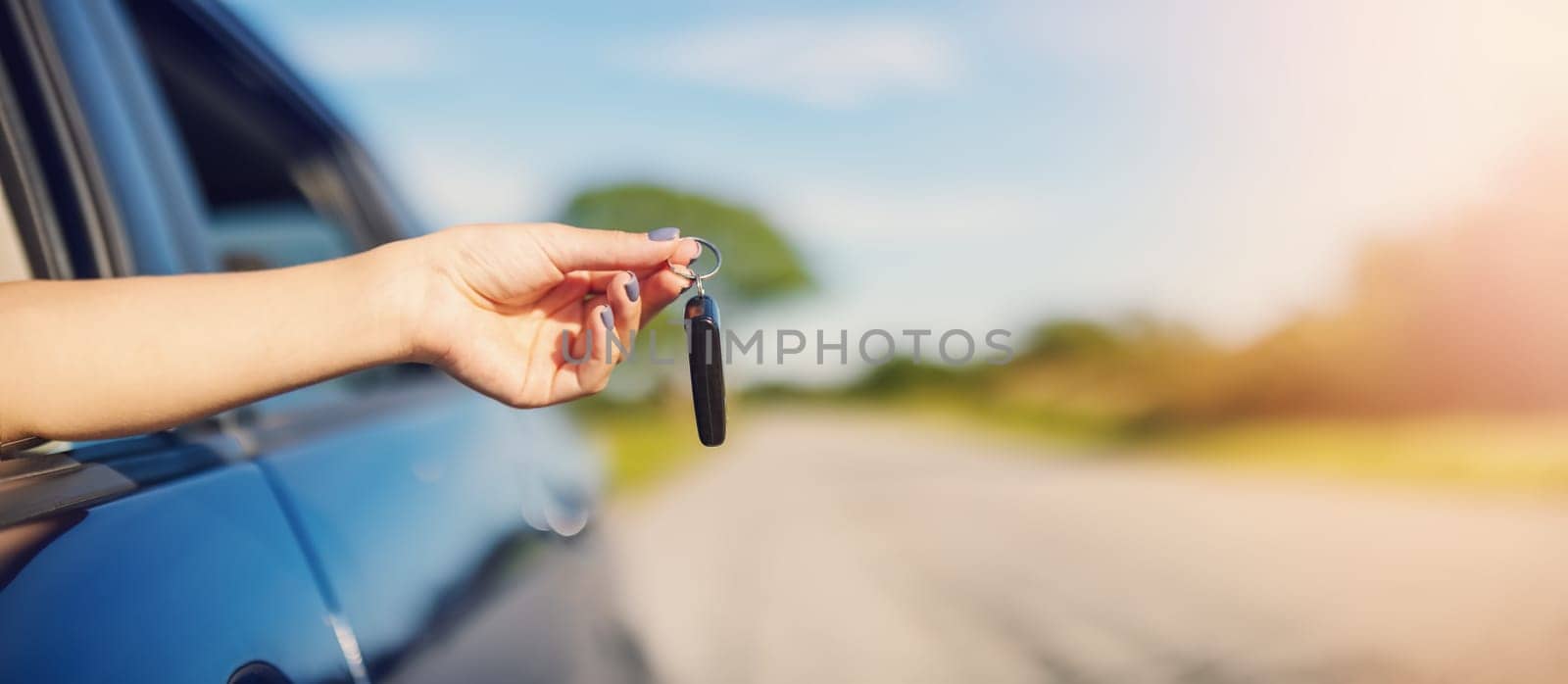 Woman's hand holding key from her new car. Concept of buying and selling ofthe automobile.